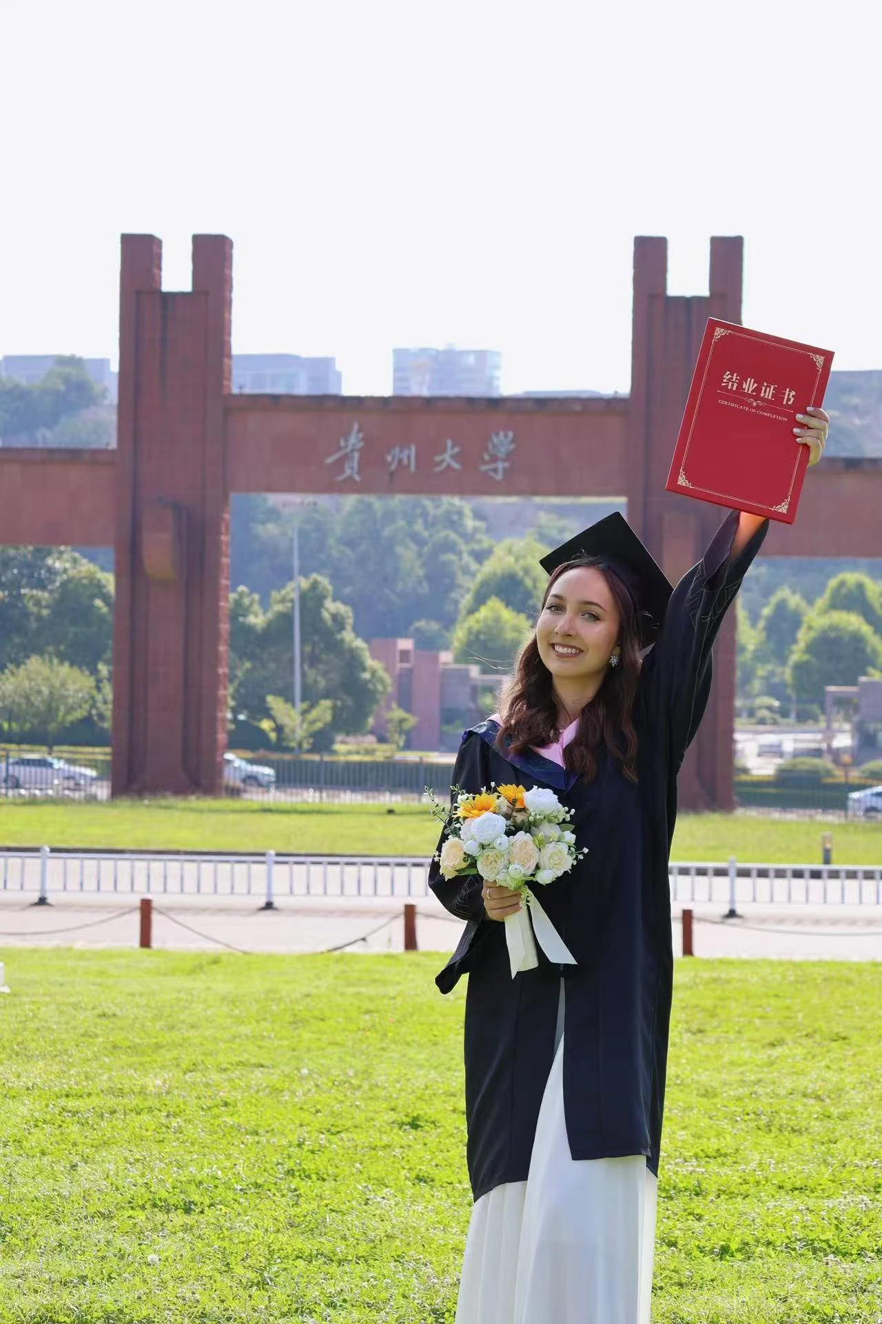 Выпускница поднимает сертификат о завершении программы у Guizhou University